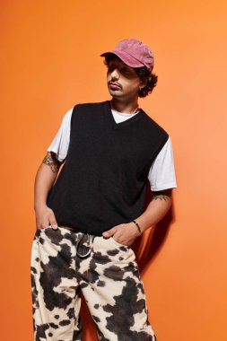 Genç adam, şık bir şapkası ve şık pantolonu olan eşsiz bir kıyafet sergiliyor..