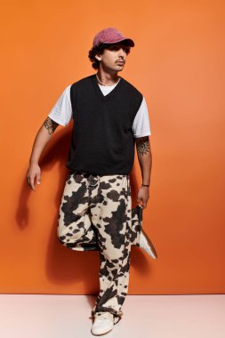 Yakışıklı genç bir adam modaya uygun giyinmiş, modern tarz ve yetenekle poz veriyor..