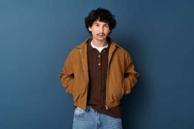Yakışıklı, modaya uygun giyinmiş genç adam yüzünde büyüleyici bir ifadeyle ayakta duruyor..
