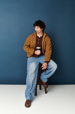 Şık bir genç adam bir taburede oturup sıcak bir içkinin tadını çıkarıyor..