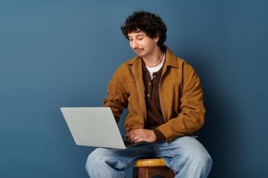 Modaya uygun genç bir adam dizüstü bilgisayarıyla meşgul, modaya uygun bir şehir alanına güven yayıyor..