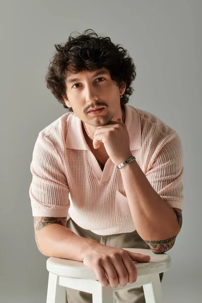 Yakışıklı bir adam şık bir elbise içinde zarif bir poz verir, kendine güven ve cazibe saçar..