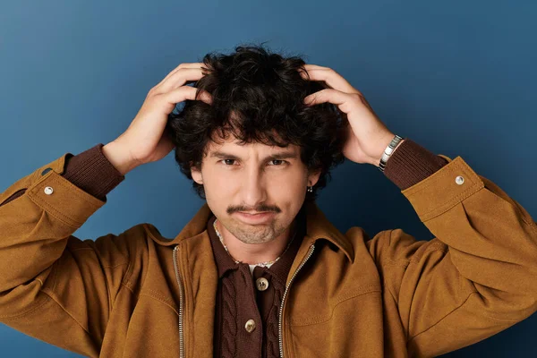 Moda kıyafetleri içinde yakışıklı bir genç ellerini saçlarında gezdiriyor, gülümsüyor..