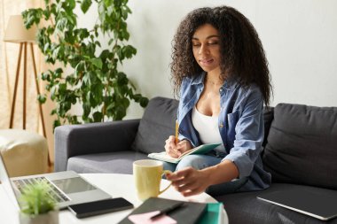 Genç siyah bir kadın sıcak bir içkinin tadını çıkarırken notlar yazıyor..