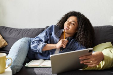 Kıvırcık saçlı kadın evde serbest iş yaparken kanepede dinleniyor..