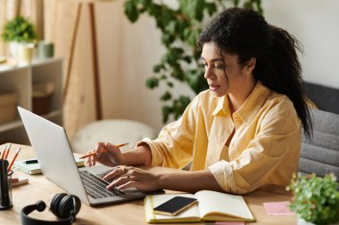 Parlak güneş ışığı modern bir daireyi dolduruyor çünkü genç bir kadın ev ofisinde özenle çalışıyor..