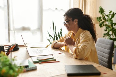 Kendini işine adamış kıvırcık saçlı genç bir kadın evde uzaktan çalışıyor ve üretkenlik yayıyor..