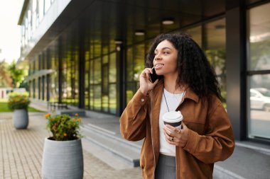 Dışarıda kahve içerken telefonda konuşan kıvırcık saçlı güzel bir genç kadın..