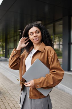 Gülümseyen Afrikalı Amerikalı bir kadın, dışarıda saçını düzeltirken sonbahar havasının tadını çıkarıyor..