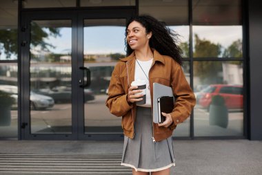 Genç bir kadın, elinde kahve ve kitaplarıyla sonbahar sezonunu şık bir şekilde kucaklıyor..