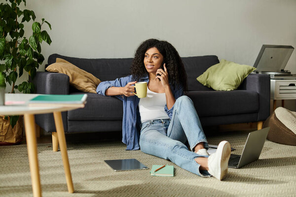 Молодая афроамериканка наслаждается удаленной работой, удобно сидя в своей современной квартире.