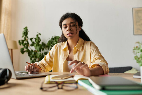 Молодая афро-американка занимается отдаленной работой на своем стильном домашнем рабочем месте.