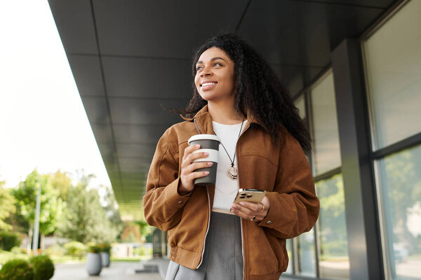 A young woman enjoys a leisurely walk, sipping her drink and admiring the autumn colors around her.