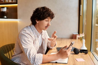 Yakışıklı genç adam, sohbete dalmış, rahat bir kafe masasında oturuyor, aletine dalmış..