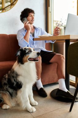 Yakışıklı genç bir adam bir kafede oturuyor, sadık köpeği yakınlarda dinlenirken bir telefon görüşmesi yapıyor..