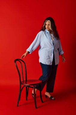 Kendine güvenen bir kadın eşsiz güzelliğini ahşap bir sandalyeyle etkileşime girerek sergiler..