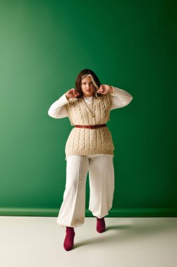 Modaya uygun bir kadın, eşsiz giysisini ve çekiciliğini çarpıcı yeşil bir arka plana karşı sergiliyor..