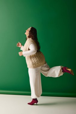 Eşsiz özelliklere sahip kendine güvenen bir kadın yeşil bir arkaplanda şakacı bir şekilde poz verir..