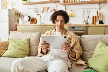 Genç profesyonel, rahat bir odada tabletle etkileşim kurarken boş zamanlardan zevk alıyor..