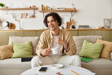 İş elbiselerindeki yakışıklı genç adam sıcak bir ortamda içkisini yudumlarken sıcacık gülümsüyor..