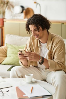 Şık giyinmiş yakışıklı genç bir adam şık bir kafede akıllı telefonunu kontrol ederken gülümsüyor..