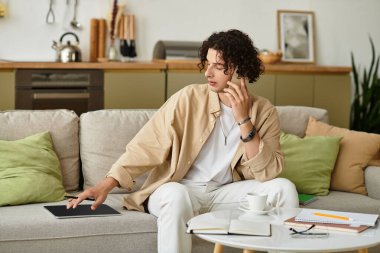 İş kıyafetleri içinde genç bir adam rahat bir çalışma alanında telefonda sohbet ediyor..