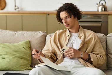 Yakışıklı genç adam koltuğa rahatça oturur, notları odaklanmış ve stil sahibi bir şekilde not alır..