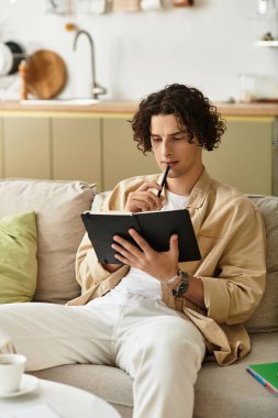 İş kıyafetli yakışıklı genç adam rahat evindeki defterine rastgele fikirler yazıyor..