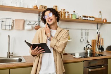 İş elbiseleri içindeki yakışıklı genç adam gülümsüyor, notlar alıyor ve şık bir mutfakta telefonda sohbet ediyor..