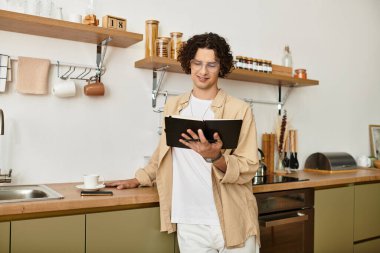Zarif genç adam notları şık bir mutfakta kahveyle eleştiriyor..