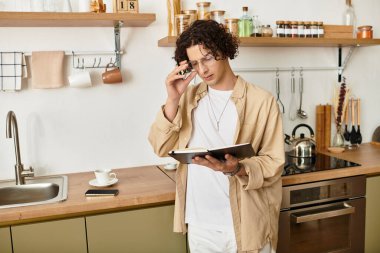 İş kıyafetli yakışıklı genç adam, aydınlık mutfakta notlar okurken güne hazırlanıyor..