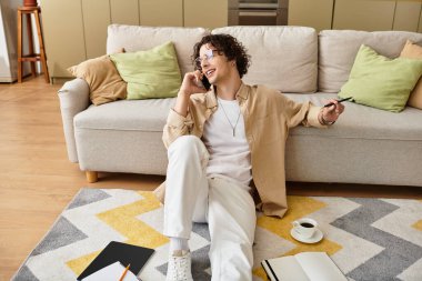 Yakışıklı bir genç adam yerde oturur, telefonda sohbet eder ve kahvesini yudumlar..