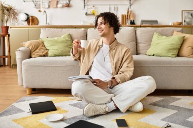 Şık bir genç adam, yaratıcı aletleriyle çevrili yerde çay içerek rahatlar..