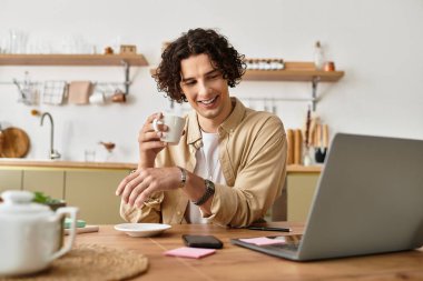 Modern bir mutfak masasında çalışırken kahvesini yudumlayan şık bir genç adam..