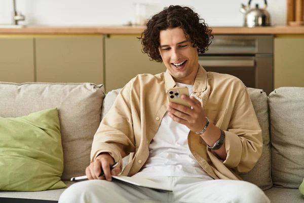 Şık bir genç adam rahat bir koltukta oturup telefonuna gülümsüyor ve boş zamanlarının tadını çıkarıyor..