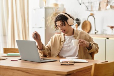 İş kıyafetleri içinde genç bir adam neşeli, şık bir mutfakta kahve içerek sohbet ediyor..