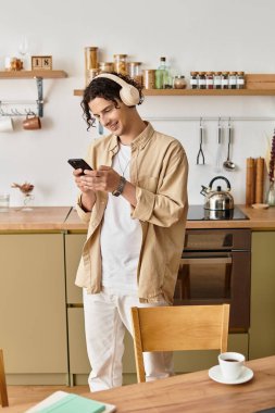 Moda kıyafetleri içindeki yakışıklı genç adam müzik dinlerken ve telefonuyla konuşurken gülümsüyor..