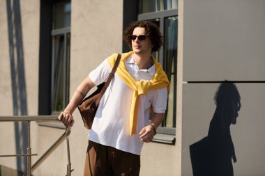 Yakışıklı genç adam, modern iş kıyafetlerine güveni somutlaştırarak dışarıda dolaşıyor..