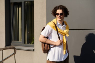 Yakışıklı genç adam şık bir kıyafet ve sırt çantasıyla gününün tadını çıkarıyor..