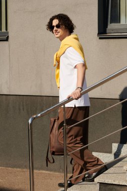 Yakışıklı ve şık giyinmiş genç adam merdivenlerden kolayca iniyor..