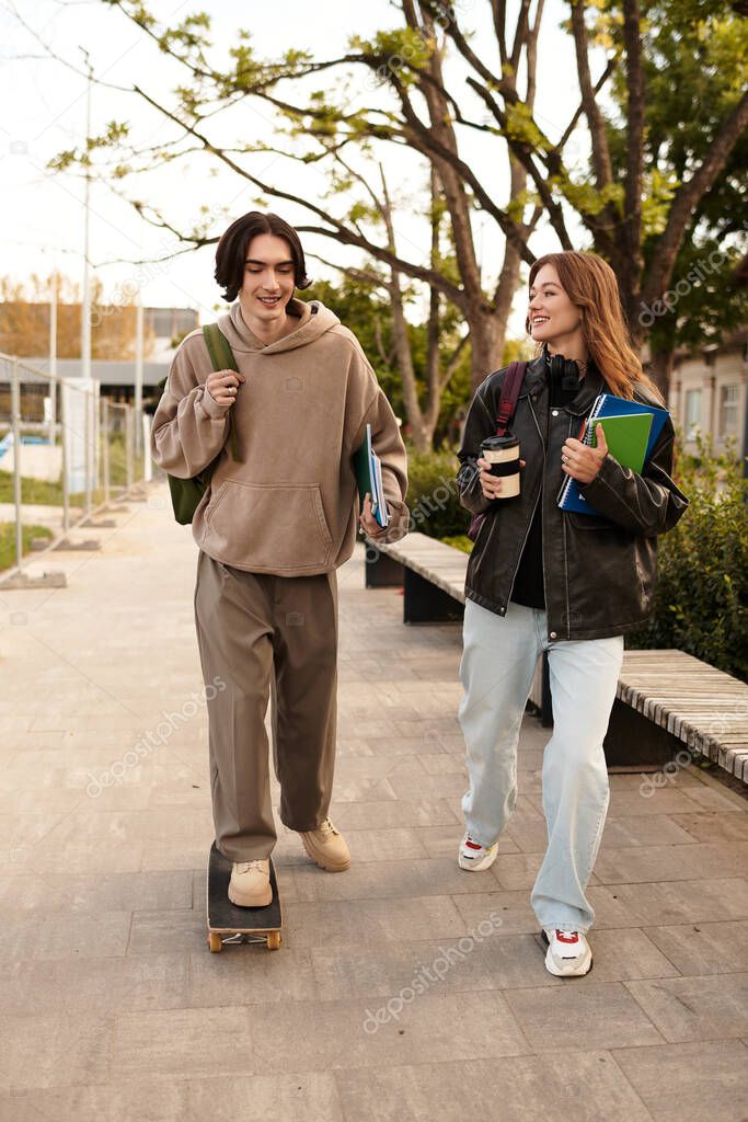 A loving couple strolls outdoors, sharing smiles and laughter, books in hand.