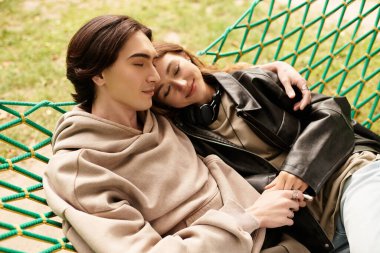 Sevgi dolu çift sıcak güneş ışığı altında bir hamakta dinlenir ve tatlı bir kucaklaşmayı paylaşır..