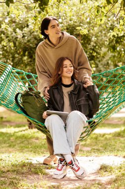 Genç bir çift, doğayla çevrili bir hamakta rahatlarken birlikte vakit geçirmekten zevk alır..