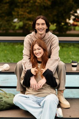 Neşeli bir çift parkta oturur, birbirlerini kucaklarlar ve güneşin sıcaklığının tadını çıkarırlar..