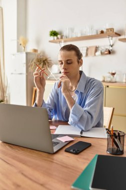 Genç yakışıklı bir adam düşünceli bir şekilde masasında oturuyor. Dizüstü bilgisayarında yaratıcı işlere dalmış..
