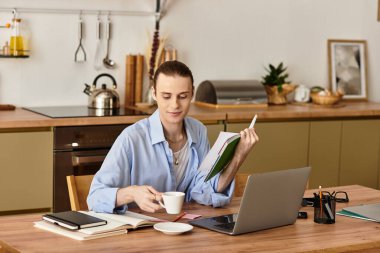 Genç bir adam, elinde bir kahve fincanı ve kitapla, tahta bir masada rahatlıyor..