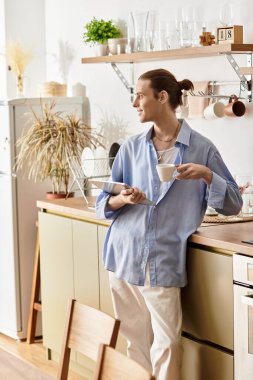 Göz alıcı genç bir adam mutfak tezgahına yaslanmış kahvesinin tadını çıkarıyordu..