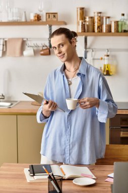 Genç, çekici bir adam elinde bir kahve fincanı ve pano tutuyor..