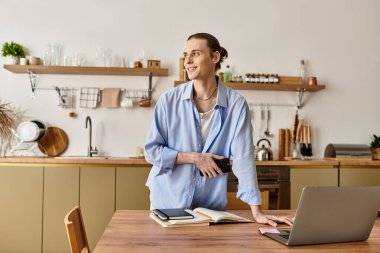 Parlak mutfak ortamında genç bir adam dizüstü bilgisayar ve dizüstü bilgisayarla fikirleri keşfediyor..