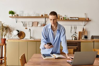 Sıcak ve davetkar bir mutfakta genç bir kadın, ahşap bir masada telefonuna odaklanır..